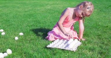 Little beautiful girl is preparing for Easter with a tray of white eggs photo