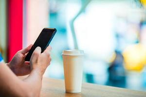 Closeup of male hands holding cellphone and glass of coffee in cafe. photo