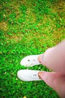 Closeup of female legs in sneakers on the grass outdoors in the park. photo