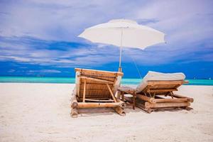 Paradise view of nice tropical empty sandy plage with umbrella and beach chair photo
