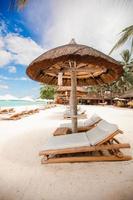 Paradise view of nice tropical empty sandy plage with umbrella and beach chair photo