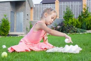 Little beautiful girl is preparing for Easter with a tray of white eggs photo