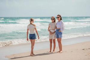 Adorable little girls and young mother on tropical white beach photo