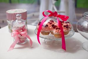 Jarra de coloridos macarons parisinos y sabrosos pasteles en la mesa de la boda foto