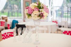 Hermoso ramo de flores brillantes en la mesa de la boda en un jarrón foto