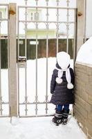 Rear view of a young girl at the gate her house on winter day photo