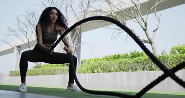 Handheld shot, Curly hair woman training her hands using rope crossfit exercise in Muscular fitness woman trains triceps program with two cables by her hands at outdoor of fitness center video