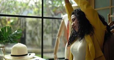 Handheld shot, young beautiful asian designer woman raised her arms and twisted body to relieve fatigue while working in tailor shop, Startup small business entrepreneur concept video