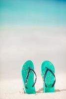Summer mint flip flops with sunglasses on white beach photo