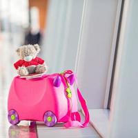 Closeup pink small kids suitcase in airport near window photo