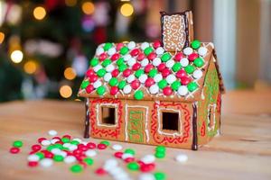 Gingerbread house decorated with colorful candies background Christmas tree lights photo