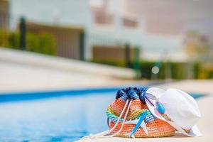 bolsa de playa colorida, vaso de jugo, sombrero de paja y modelo de avión en mano femenina en vacaciones de verano foto