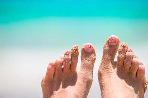 cerca de pies femeninos en la playa de arena blanca foto