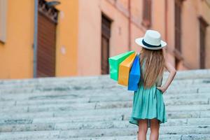 Adorable little girl walking with shopping bags outdoors in Rome. Fashion toddler kid in Italian city with her shopping photo