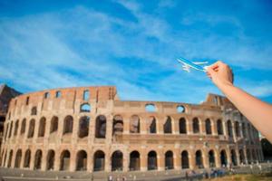 Closeup toy airplane on Colosseum background. Italian european vacation in Rome. Concept of travel imagination. photo