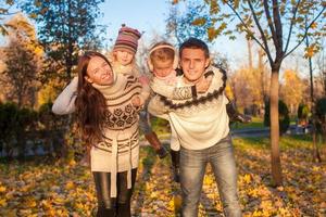 familia de cuatro con dos niños divirtiéndose en el parque de otoño en un día cálido y soleado foto