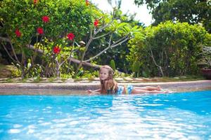 Little adorable girl in the swimming pool looks at camera photo