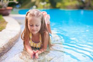 Closeup of Cute little girl in the swimming pool looks at camera photo