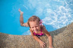 niña linda con flor detrás de la oreja en la piscina foto