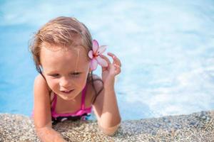 Little cute girl with flower behind her ear in the swimming pool photo