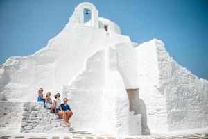 vacaciones familiares en europa. padres e hijos en la calle del típico pueblo tradicional griego con paredes blancas y puertas coloridas en la isla de mykonos foto