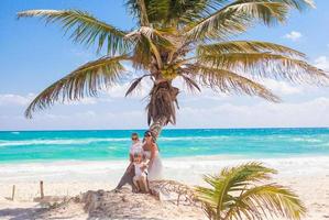 mamá con dos hijas en una palmera disfrutando de vacaciones en la playa foto