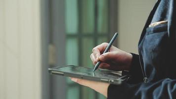 Group of businesspeople using a digital tablet together in front of office building windows overlooking the city video