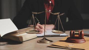 Business and lawyers discussing contract papers with brass scale on desk in office. Law, legal services, advice, justice and law concept picture with film grain effect video