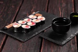 rollo de sushi maki con aguacate de salmón y caviar tobiko servido en el primer plano de la pizarra - comida japonesa foto