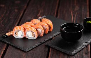 Sushi roll philadelphia with salmon and eel and cream cheese on black background close-up. Sushi menu. Japanese food concept photo