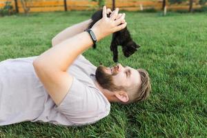 Man with little kitten lying and playing on grass - friendship love animals and pet owner concept photo