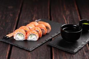 Sushi roll philadelphia with salmon and cream cheese on black background close-up. Sushi menu. Japanese food concept photo