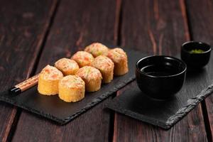 Sushi roll with mayonnaise sauce served on black board and soy sauce. photo