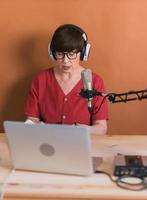 Middle-aged female radio presenter talking into the microphone and reading news - radio broadcast online concept photo