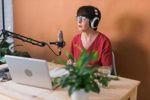 Middle-aged woman radio host making podcast recording for online show - broadcast and dj concept photo