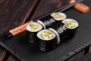 Maki sushi roll with cucumber and sesame with chopsticks close-up. Sushi menu. Japanese food. photo