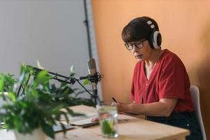 Mature woman making podcast recording for her online show. Attractive business woman using headphones front of microphone for a radio broadcast photo