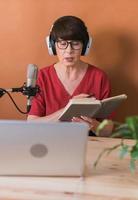 Woman making podcast recording for her online show. Attractive business woman using headphones front of microphone for a radio broadcast photo