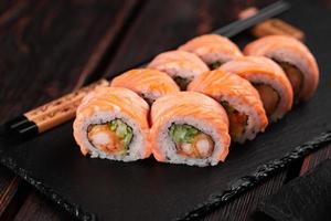Sushi roll philadelphia with crab and cucumber and cream cheese, caviar on black background close-up. Sushi menu. Japanese food concept photo