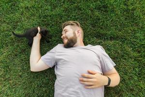 hombre con gatito acostado y jugando en la hierba - amistad amor animales y concepto de dueño de mascota foto