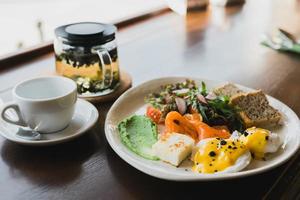 desayuno ligero y abundante, brunch con huevos revueltos, tostadas de pan integral y salmón ahumado y guacamole. servido con una mezcla de rúcula y rábano foto