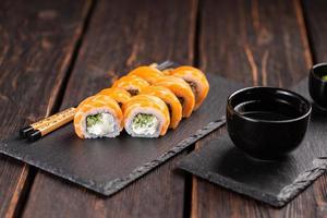 Sushi roll philadelphia with salmon and cucumber and cream cheese on black background. Sushi menu. Japanese food concept photo