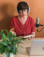 Middle-aged woman radio host making podcast recording for online show - broadcast and dj concept photo