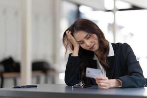 una joven compradora asiática infeliz tiene problemas para comprar en línea en Internet en un smartphone con tarjeta de crédito. mujer frustrada enojada confundida con la pérdida de dinero de la cuenta comprando en la web en el teléfono celular. foto