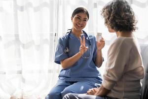Healthcare worker or nurse caregiver giving pills, showing a prescription drug to senior woman. Elderly healthcare concept