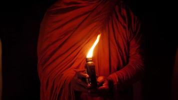 plano médio portátil, cena noturna, close-up da mão do monge segurando uma pequena garrafa iluminada por uma lâmpada de querosene video