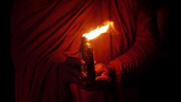 Handheld shot, night scene, Close up hand of monk holding a little bottle lit by a kerosene lamp video