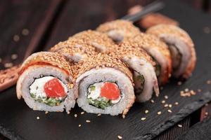 rollo de sushi con anguila ahumada y salmón con primer plano de pepino y queso. delicioso juego de rollos de sushi fresco tradicional. menú de sushi restaurante de cocina japonesa. comida asiática foto