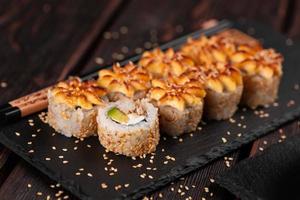 rollo de sushi con anguila ahumada con primer plano de aguacate y queso. delicioso juego de rollos de sushi fresco tradicional. menú de sushi restaurante de cocina japonesa. comida asiática foto