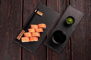 Sushi roll philadelphia with salmon and cucumber and cream cheese on black background top view. Sushi menu. Japanese food concept photo